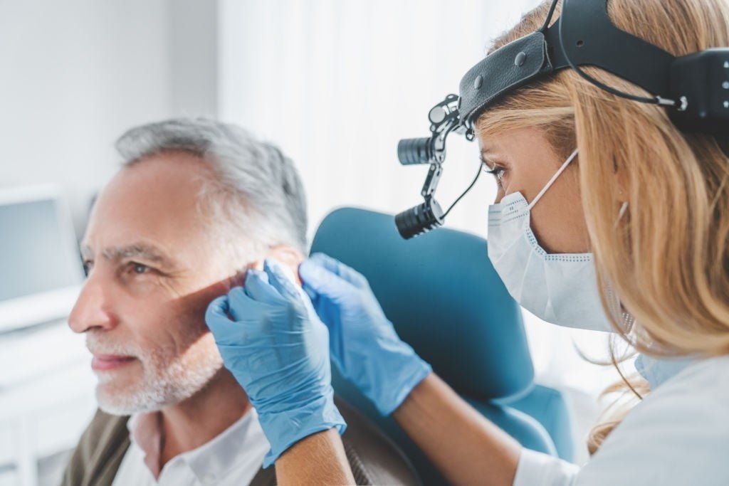Mature patient with hearing problem visiting doctor otolaryngologist