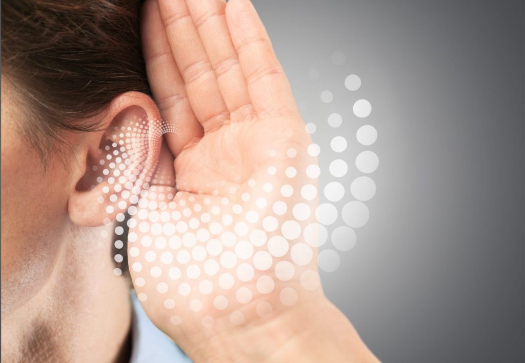 Side view of a person cupping their ear with hand