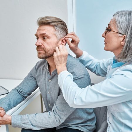 Experienced,Female,Doctor,Fitting,Intra-the-ear,Hearing,Aid,Into,Patient's,Ear
